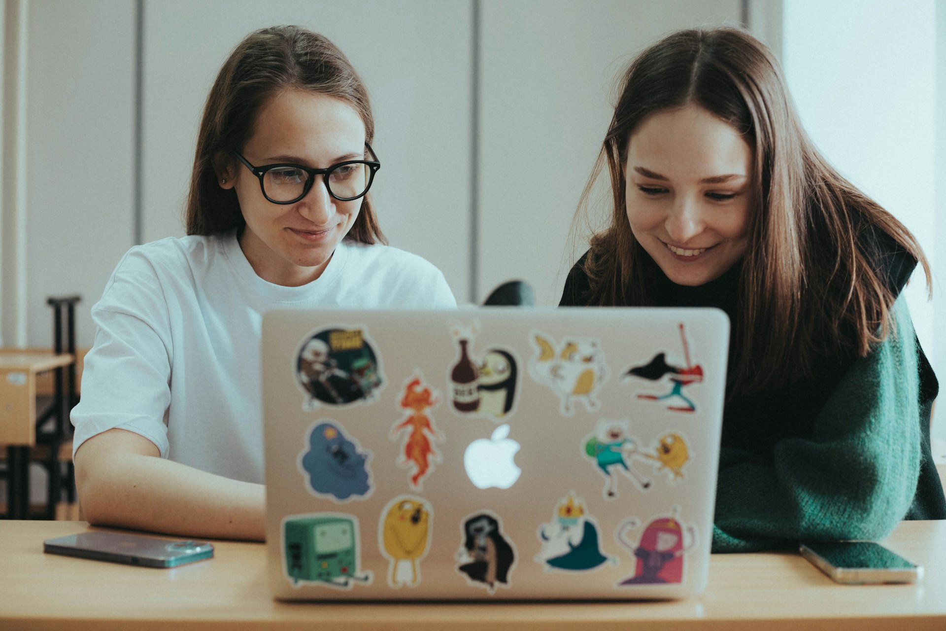 a couple of women sitting at a table with a laptop